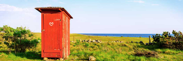Ett rött utedass i ett öppet landskap vid havet.